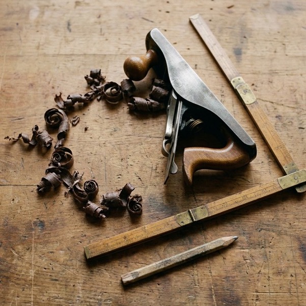 A hand plane and wood shavings on a workbench
